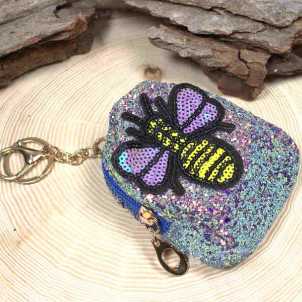 Glitzerndes Schlüsselanhänger Mäppchen in Bunt mit detailreichem Biene-Motiv, geschlossen, zur Verwendung als Mini-Utensilientasche oder Schlüsselorganizer. Glitzerndes Schlüsselanhänger Mäppchen in Bunt mit detailreichem Biene-Motiv, geschlossen, zur Verwendung als Mini-Utensilientasche oder Schlüsselorganizer.
