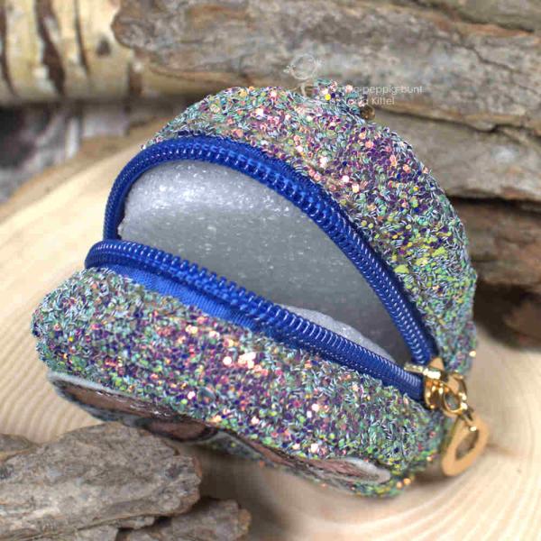 Nahaufnahme des glitzernden Stoff-Materials der kleinen schwarzen Utensilientasche und des Reißverschlusses.
