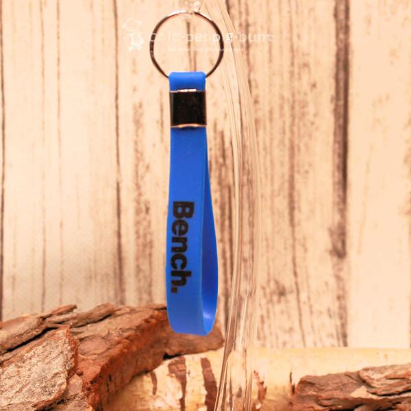 Sportlicher Bench Schlüsselanhänger aus schwarzem PVC-Band mit weißem Schriftzug und Metallring.