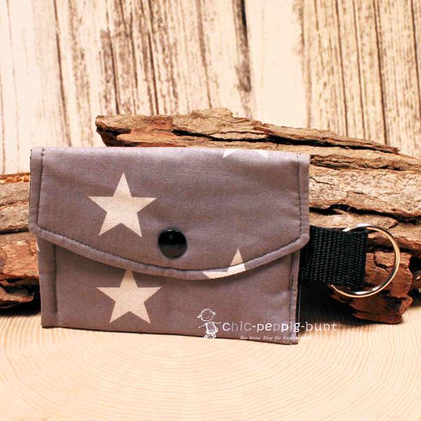 Handgenähtes buntes Schlüsselmäppchen aus Stoff mit Kunststoff-Druckknopf und silbernem Schlüsselring auf hellem Hintergrund.