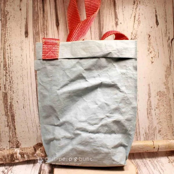 Nachhaltige hellblaue Shoppertasche aus waschbarem Papier mit auffälligem orangem Schulterband, handgefertigt von Maxx Factory.