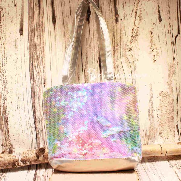 Kleine lila-blau schimmernde Kindertasche mit Pailletten-Stickerei, silbernem Boden und grauen Kunstleder-Griffen auf rustikalem Holzgrund.