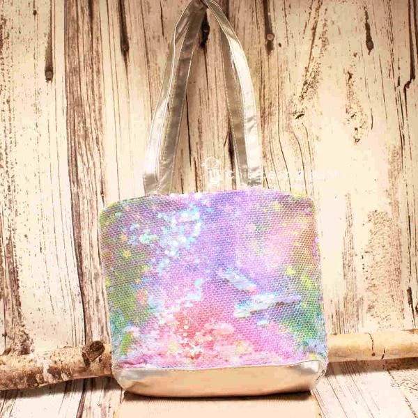 Kleine lila-blau schimmernde Kindertasche mit Pailletten-Stickerei, silbernem Boden und grauen Kunstleder-Griffen auf rustikalem Holzgrund.