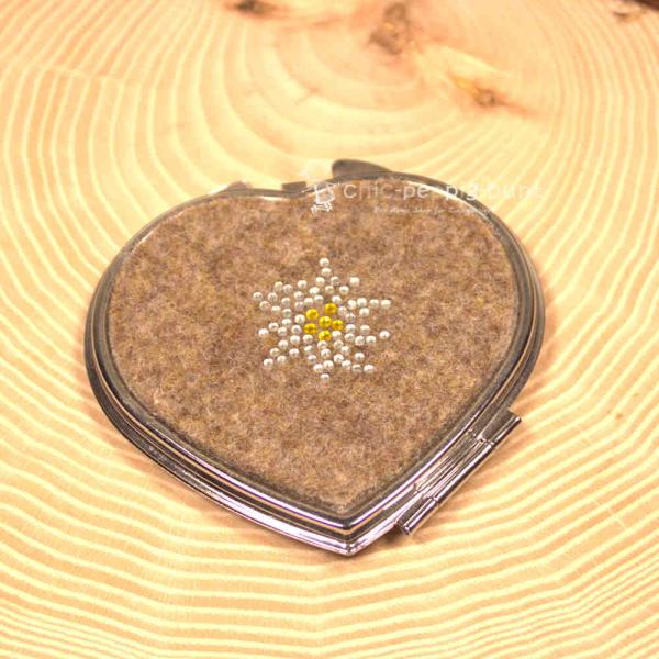 Kompakter, herzförmiger Handspiegel aus Filz, verziert mit einem Edelweiß-Motiv aus glitzernden Strasssteinen. Perfektes Trachtenaccessoire für unterwegs. Kompakter, herzförmiger Handspiegel aus Filz, verziert mit einem Edelweiß-Motiv aus glitzernden Strasssteinen. Perfektes Trachtenaccessoire für unterwegs.