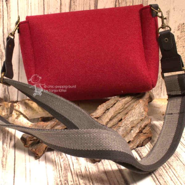 Rote Filz Handtasche quer getragen, zeigt die Maße und das kompakte Design. Rote Filz Handtasche quer getragen, zeigt die Maße und das kompakte Design.
