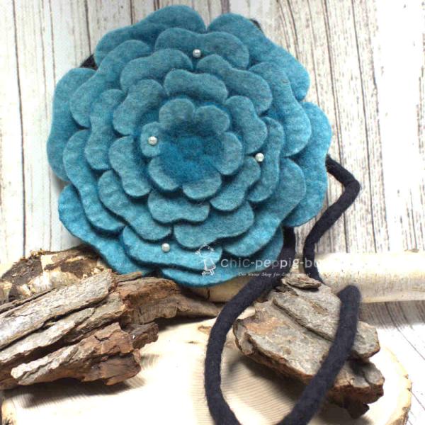 Runde türkisfarbene Umhängetasche aus Filz in Blumenform mit glitzernden Perlen und schwarzem Innenfutter.