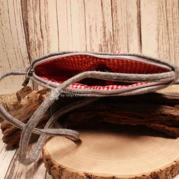 Innenansicht der Herz-Filztasche mit rot-weiß kariertem Futter und offenem Reißverschluss.