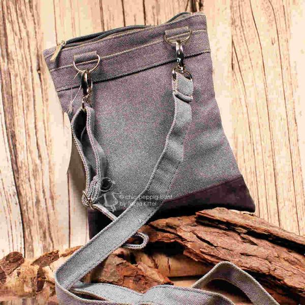 Rückseite der Stoff-Handtasche mit Fokus auf die silbernen Karabinerhaken des abnehmbaren Schulterbands.