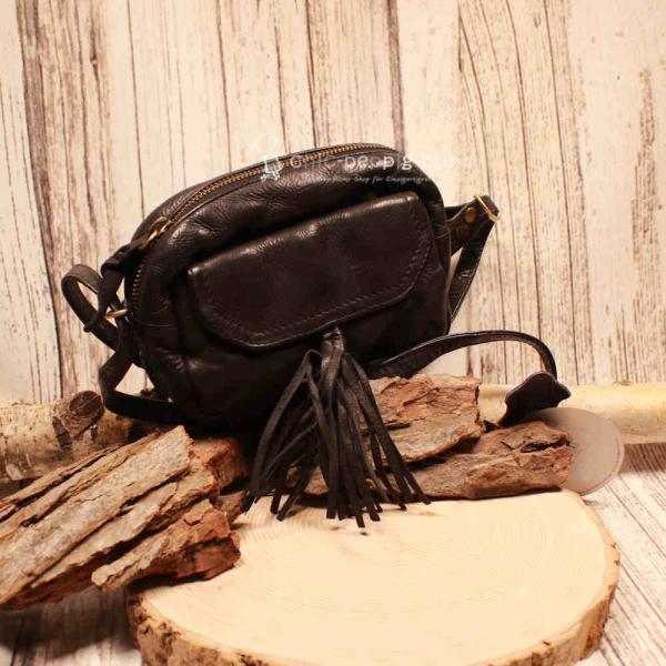 Kleine schwarze Umhängetasche aus Leder mit zwei dekorativen Quasten am Magnetverschluss und verstellbarem Schulterriemen.