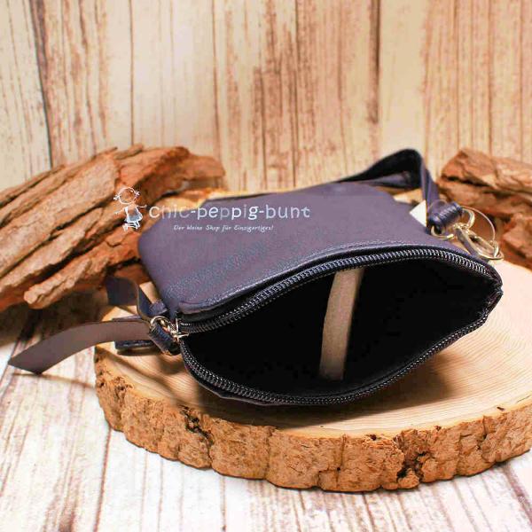 Geöffnetes Fach der blauen Ledertasche mit Platz für Smartphone und Essentials.