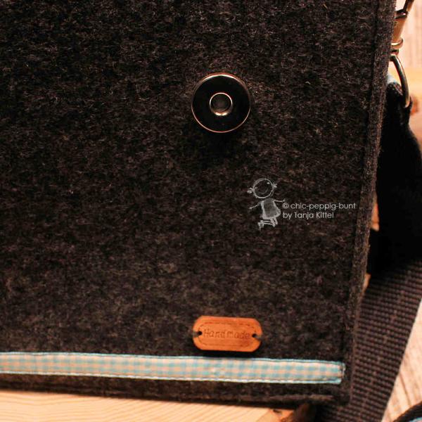 Nahaufnahme eines geschlossenen Magnetknopfs und des edlen Leder-Labels mit der Prägung Handmade.