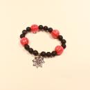 Elastisches Handmade Armband mit großen orange-schwarzen Kürbisperlen und silberfarbenem Spinnennetz-Anhänger.