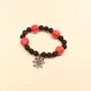 Elastisches Handmade Armband mit großen orange-schwarzen Kürbisperlen und silberfarbenem Spinnennetz-Anhänger.