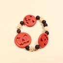 Elastisches Handmade Armband mit großen orangefarbenen Kürbisperlen und kleinen schwarzen Totenkopfperlen im Wechsel.