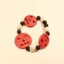 Elastisches Handmade Armband mit großen orangefarbenen Kürbisperlen und kleinen schwarzen Totenkopfperlen im Wechsel.