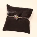 : Versilbertes Gliederarmband mit bunter Schildkröte präsentiert auf einem schwarzen Schmuckkissen.
