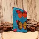 Handgenähtes Brillenetui von chic-peppig-bunt in Blau mit Schmetterlings-Motiv und pink-weiß gepunktetem Blumen-Innenstoff auf hellem Hintergrund.