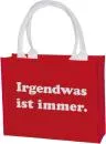 Rote Shoppertasche aus Polyester mit weißem Aufdruck „Irgendwas ist immer“ und stabilen Griffen.