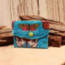 Kleiner handgenähter Geldbeutel von chic-peppig-bunt aus blauem Stoff mit Schmetterlingen und weiß-grün gepunktetem Futter auf hellem Hintergrund.