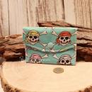 Kleiner handgenähter Geldbeutel von chic-peppig-bunt aus blauem Stoff mit Totenköpfen und rosa gepunktetem Innenfutter auf hellem Hintergrund.