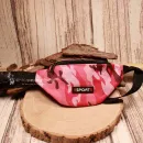 Vorderansicht der pinken Camouflage-Gürteltasche für Kinder mit Sport-Schriftzug auf einer Holzscheibe.