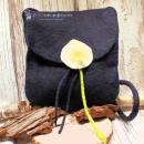 Flache dunkelblaue Handtasche aus Filz mit aufgenähter weißer Calla-Blüte, schwarzem Innenfutter und langem Schulterband vor neutralem Hintergrund.