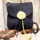 Flache dunkelblaue Handtasche aus Filz mit aufgenähter weißer Calla-Blüte, schwarzem Innenfutter und langem Schulterband vor neutralem Hintergrund.