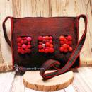 Handgefertigte graue Filztasche mit aufgenähten Bommeln in Pink, Rot und Lila sowie einer silbernen Metallperle vor hellem Hintergrund.