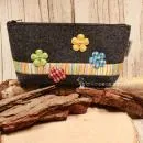 Handgenähte weidräwöl Kosmetiktasche aus dunkelgrauem Filz mit Blumen und bunter Streifenbordüre.