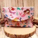 Großer handgenähter Geldbeutel von chic-peppig-bunt aus rosa Stoff mit Meerjungfrauen und pink gepunktetem Innenfutter auf hellem Hintergrund.