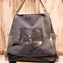 Grauer Rucksack aus Stoff mit silbernem Pailletten-Herz, braunem Lederboden und gestreiften Gurten, 3-in-1 Funktion als Handtasche.