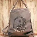 Grauer Rucksack aus Stoff mit silbernem Ying & Yang Symbol aus Pailletten, Lederboden und gestreiften Gurten, 3-in-1 Funktion als Handtasche.