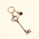 Versilberter Schlüsselanhänger mit großem Schlüssel-Motiv und einem abnehmbaren schwarzen Schutzengel-Anhänger mit Strass-Flügeln.