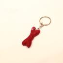 Handgefertigter Mini Knochen aus bordeauxrotem Filz als witziger Schlüsselanhänger und weicher Taschenbaumler, Gesamtansicht und Detailaufnahme.