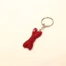 Handgefertigter Mini Knochen aus bordeauxrotem Filz als witziger Schlüsselanhänger und weicher Taschenbaumler, Gesamtansicht und Detailaufnahme.