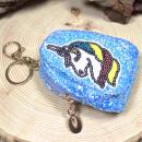 Kleines, blaues Mäppchen mit Glitzer und Einhorn-Motiv als Schlüsselanhänger.