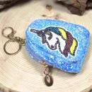 Kleines, blaues Mäppchen mit Glitzer und Einhorn-Motiv als Schlüsselanhänger.