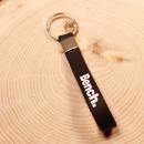 Schwarzer Bench Schlüsselanhänger aus Kautschuk mit weißem Schriftzug und silbernem Metallring.