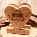 Stehender Serviettenhalter aus hellem Holz in Herzform mit Gravur Alpenliebe auf einer Holzscheibe.
