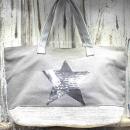 Große graue Shoppertasche mit silbernem Pailletten-Stern, weißem Boden-Element und grauen Kunstleder-Tragegriffen vor rustikalem Holzhintergrund.