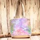 Kleine lila-blau schimmernde Kindertasche mit Pailletten-Stickerei, silbernem Boden und grauen Kunstleder-Griffen auf rustikalem Holzgrund.