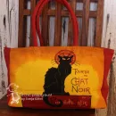 Stoff-Shoppertasche Chat Noir in Gelb und Rot mit Motiv einer schwarzen Katze, Reißverschluss und roten Tragegriffen.