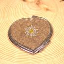 Kompakter, herzförmiger Handspiegel aus Filz, verziert mit einem Edelweiß-Motiv aus glitzernden Strasssteinen. Perfektes Trachtenaccessoire für unterwegs.