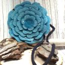 Runde türkisfarbene Umhängetasche aus Filz in Blumenform mit glitzernden Perlen und schwarzem Innenfutter.