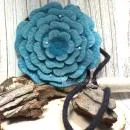 Runde türkisfarbene Umhängetasche aus Filz in Blumenform mit glitzernden Perlen und schwarzem Innenfutter.