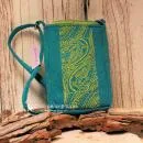 Kleine grüne Filz-Handtasche für Damen mit Reißverschluss und langem Schultergurt auf hellem Untergrund.
