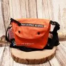 Kleine orangefarbene Umhängetasche aus Nylon mit weißem Be Brave Schriftzug auf der Vorderseite.